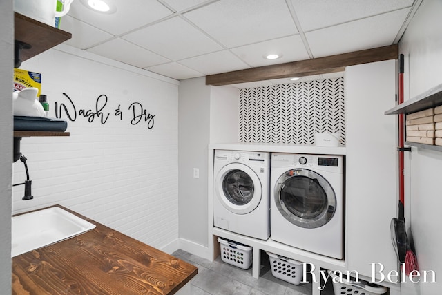 laundry room featuring brick wall and washer and clothes dryer