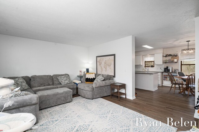 living room featuring a notable chandelier, dark wood-type flooring, and a textured ceiling