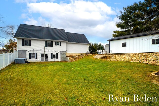 back of property with central AC unit and a lawn
