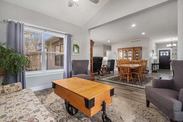 living room with lofted ceiling, ceiling fan with notable chandelier, and light hardwood / wood-style floors