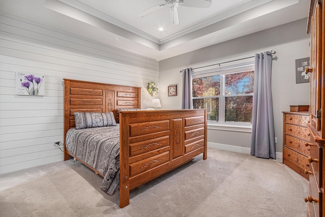 carpeted bedroom featuring a raised ceiling, ceiling fan, and wooden walls