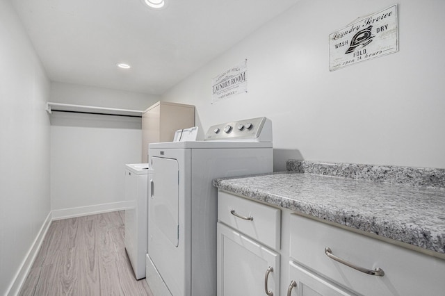 laundry room with cabinets, washer and clothes dryer, and light hardwood / wood-style flooring