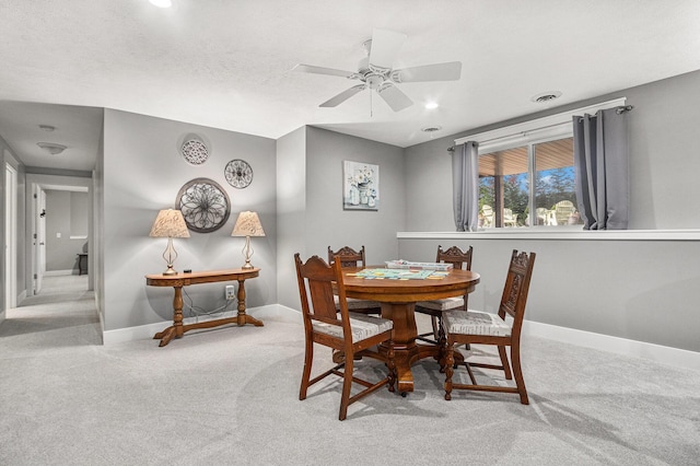 carpeted dining space with a textured ceiling and ceiling fan