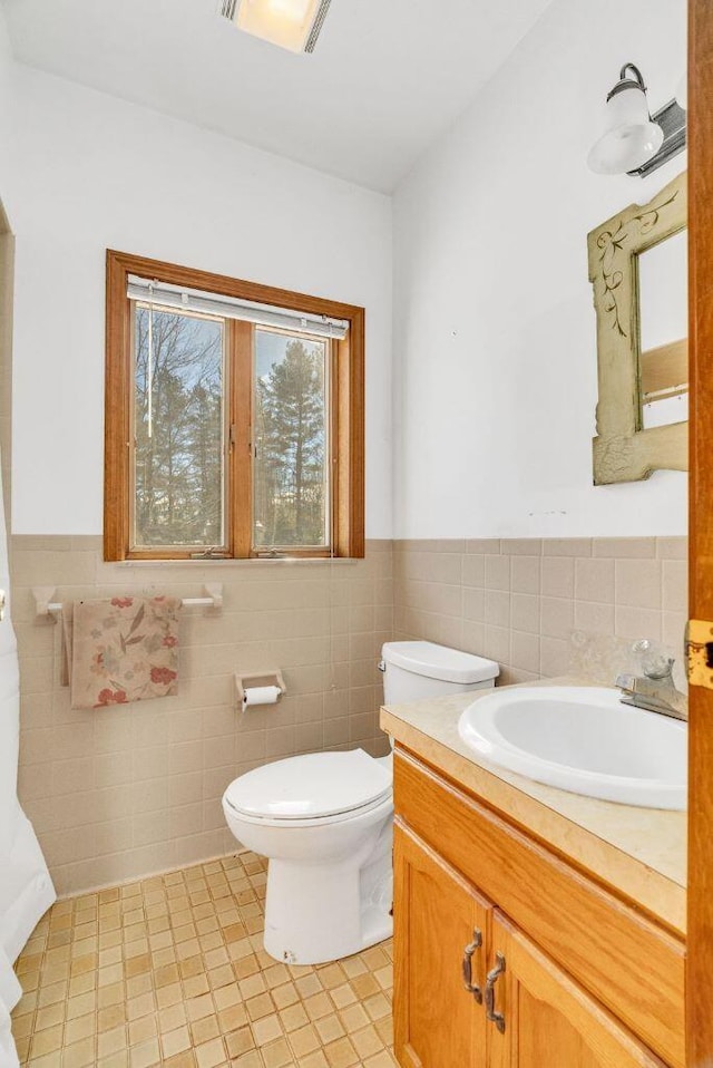 bathroom with vanity, toilet, and tile walls