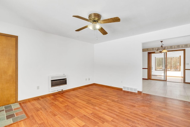 unfurnished room featuring heating unit, light hardwood / wood-style floors, and ceiling fan