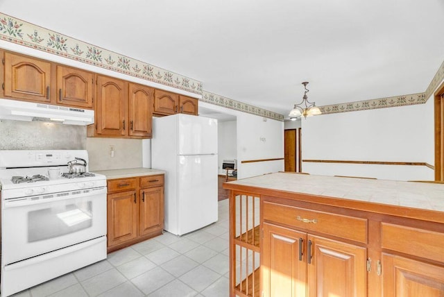 kitchen featuring pendant lighting, tile counters, a notable chandelier, light tile patterned floors, and white appliances