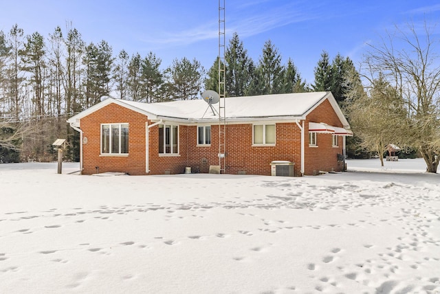 snow covered rear of property featuring cooling unit