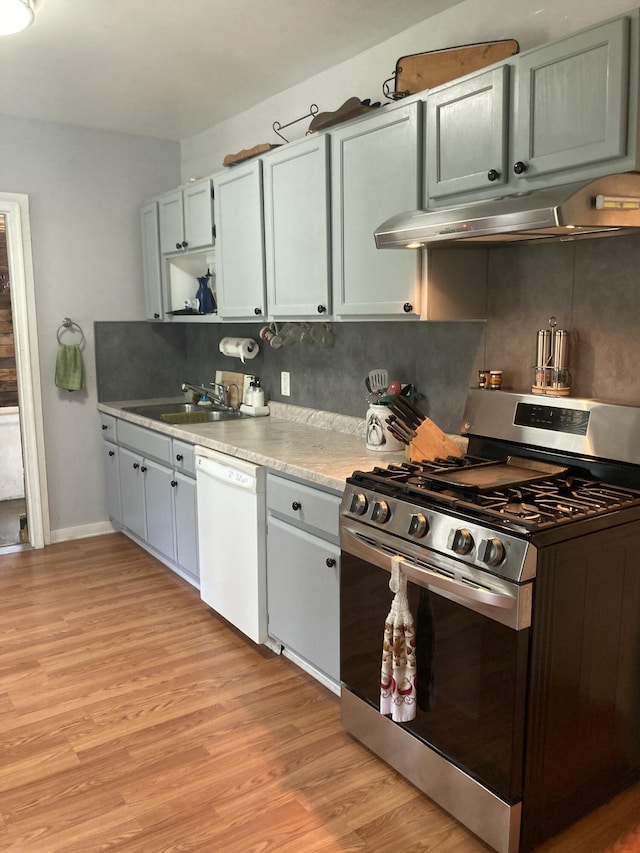 kitchen with stainless steel gas stove, dishwasher, sink, decorative backsplash, and light hardwood / wood-style floors