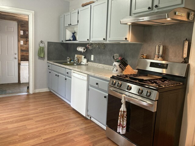 kitchen featuring sink, gas range, light hardwood / wood-style flooring, white dishwasher, and decorative backsplash