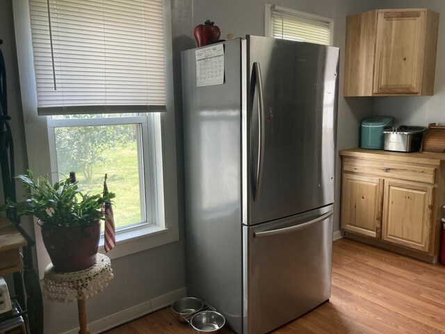 kitchen with light brown cabinetry, stainless steel refrigerator, and light hardwood / wood-style flooring