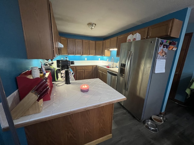 kitchen featuring appliances with stainless steel finishes, tile counters, kitchen peninsula, and sink