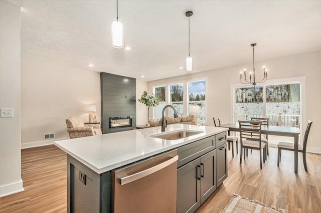 kitchen featuring pendant lighting, a fireplace, dishwasher, sink, and a kitchen island with sink