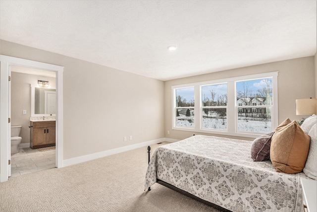 carpeted bedroom with sink and ensuite bath