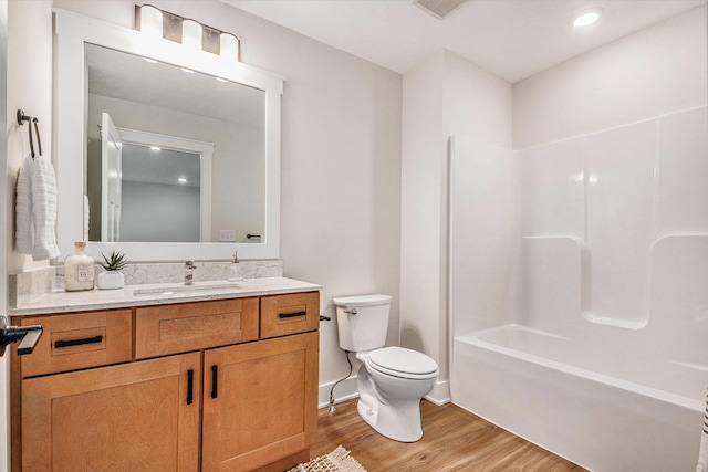 full bathroom with hardwood / wood-style flooring, vanity, shower / bathing tub combination, and toilet