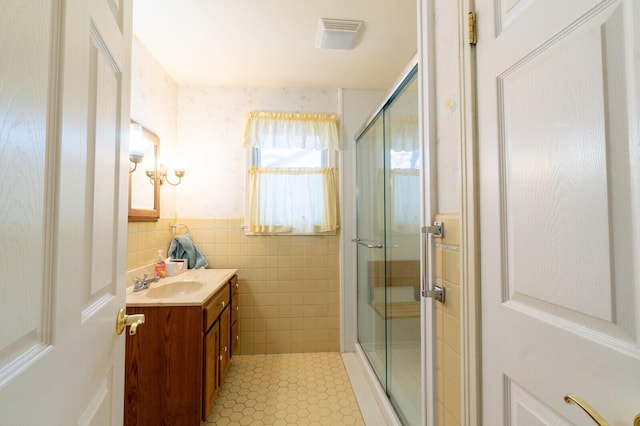 bathroom with tile walls, vanity, tile patterned flooring, and a shower with shower door