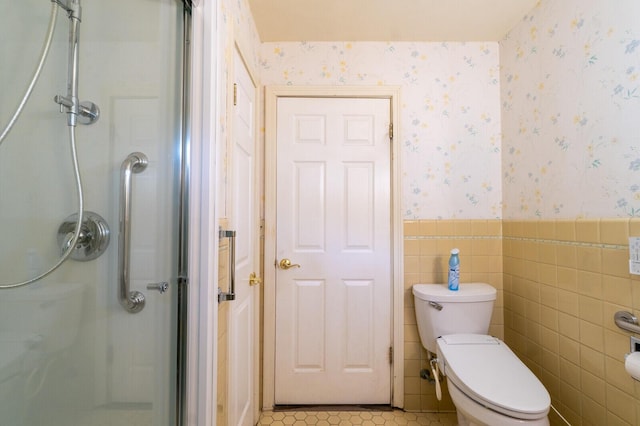 bathroom with tile walls, tile patterned flooring, a shower with shower door, and toilet