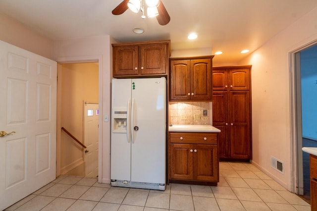 kitchen featuring white fridge with ice dispenser, light tile patterned floors, ceiling fan, and decorative backsplash