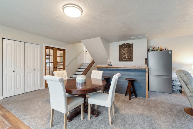 carpeted dining area featuring a textured ceiling and french doors