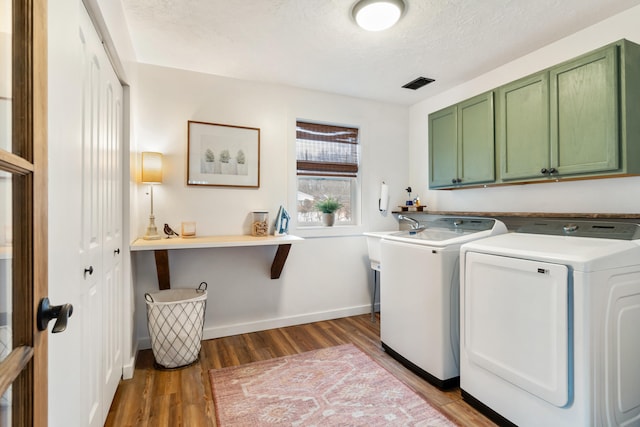 laundry area featuring independent washer and dryer, cabinets, dark hardwood / wood-style floors, and a textured ceiling