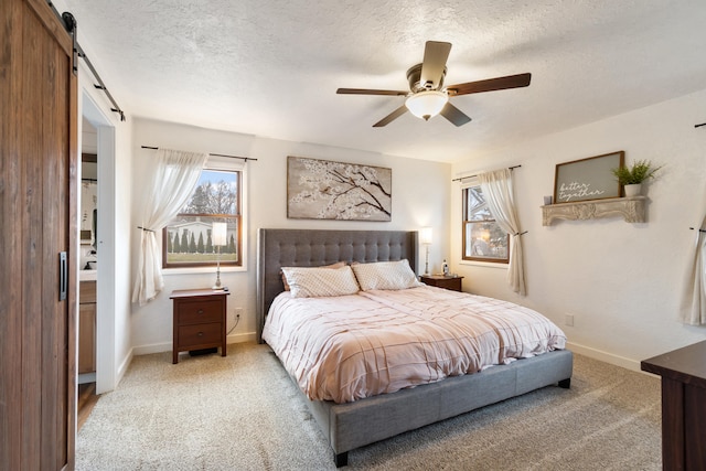 bedroom with light carpet, multiple windows, a barn door, and a textured ceiling