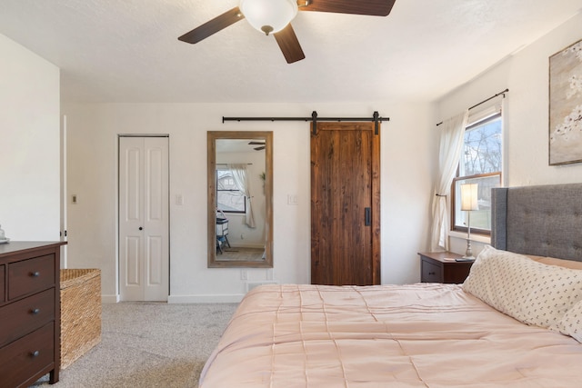 carpeted bedroom featuring a barn door and ceiling fan