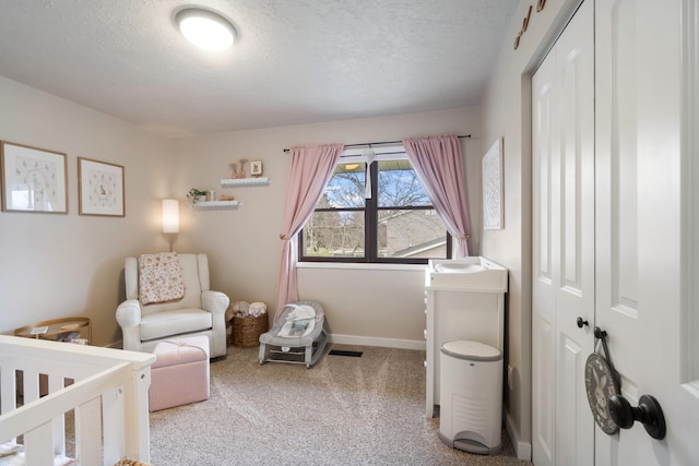 bedroom featuring a nursery area, carpet, and a textured ceiling