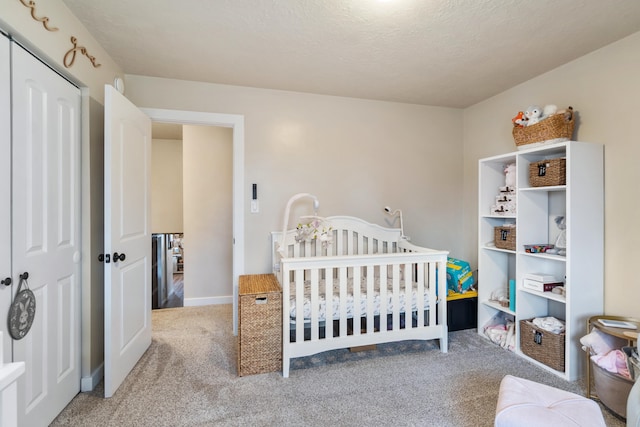 carpeted bedroom featuring a closet, a nursery area, and a textured ceiling