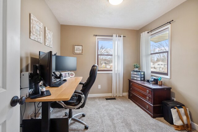 office with a healthy amount of sunlight, light carpet, and a textured ceiling