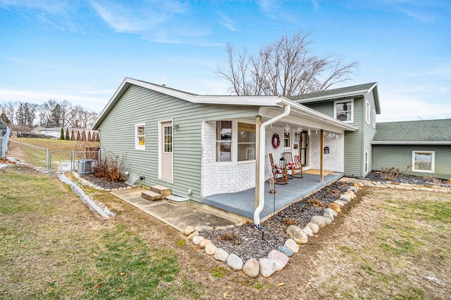 view of front of property featuring cooling unit, a front yard, and a patio area