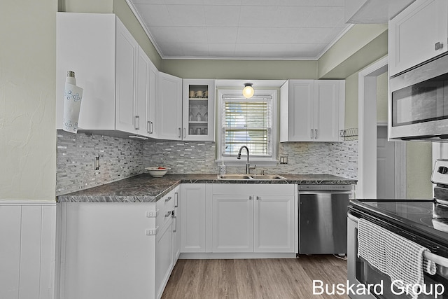 kitchen featuring appliances with stainless steel finishes, light wood-type flooring, a sink, and white cabinetry