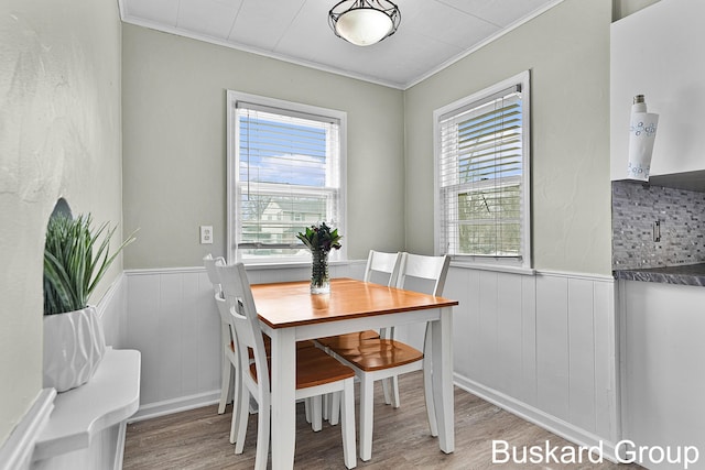 dining space with a wainscoted wall, crown molding, and wood finished floors