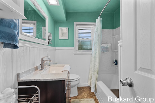 full bath with wainscoting, vanity, toilet, and shower / bath combo with shower curtain