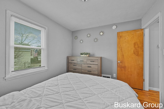 bedroom with visible vents, a textured ceiling, and wood finished floors