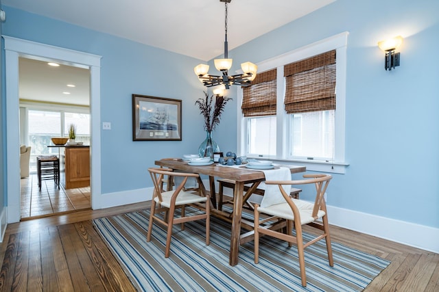 dining room featuring light wood-style flooring, baseboards, and a notable chandelier