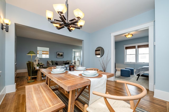 dining room featuring an inviting chandelier, baseboards, and light wood-style floors