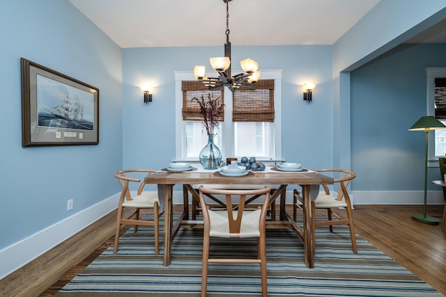 dining space featuring a chandelier, dark wood finished floors, and baseboards