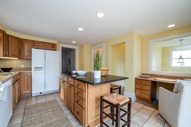 kitchen featuring white appliances, a breakfast bar area, a center island, pendant lighting, and backsplash