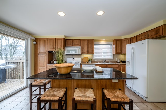 kitchen featuring a sink, white appliances, a breakfast bar area, and a kitchen island