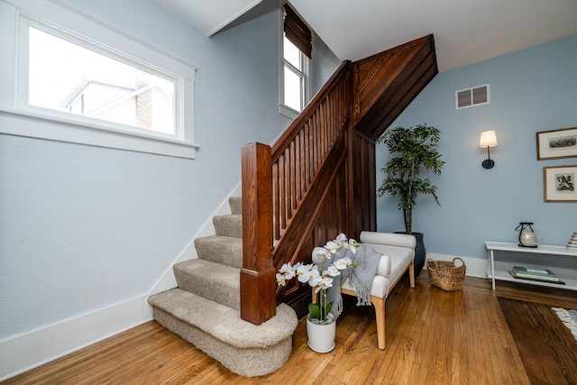 staircase with wood finished floors, visible vents, and baseboards