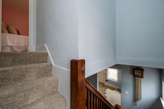 stairs featuring a textured wall and vaulted ceiling