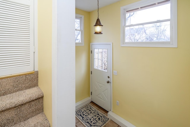 entryway with a healthy amount of sunlight, baseboards, and light tile patterned floors