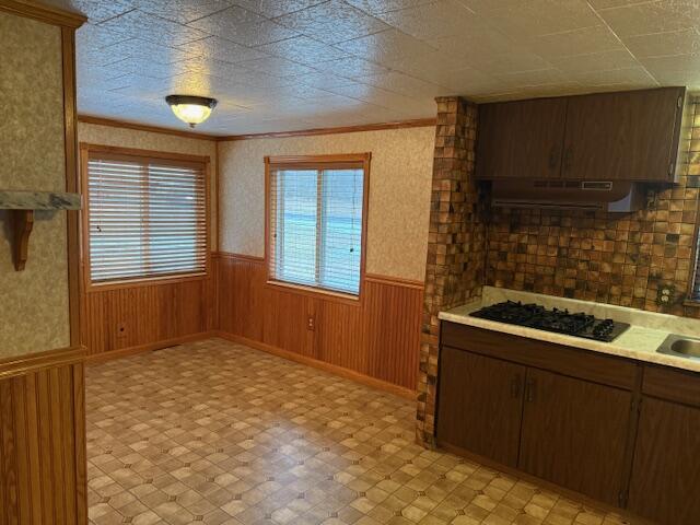 kitchen featuring ornamental molding, black gas cooktop, and wood walls