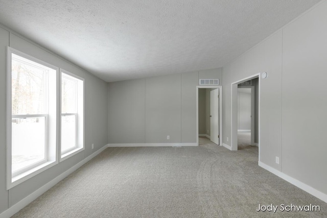 empty room with light carpet and a textured ceiling