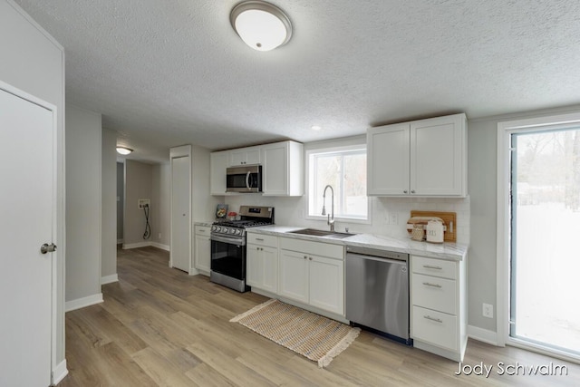 kitchen with white cabinetry, stainless steel appliances, light hardwood / wood-style floors, and sink