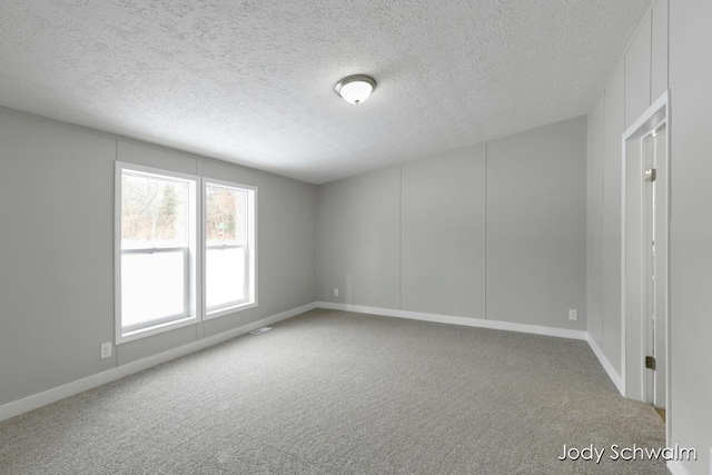 unfurnished room featuring carpet flooring and a textured ceiling