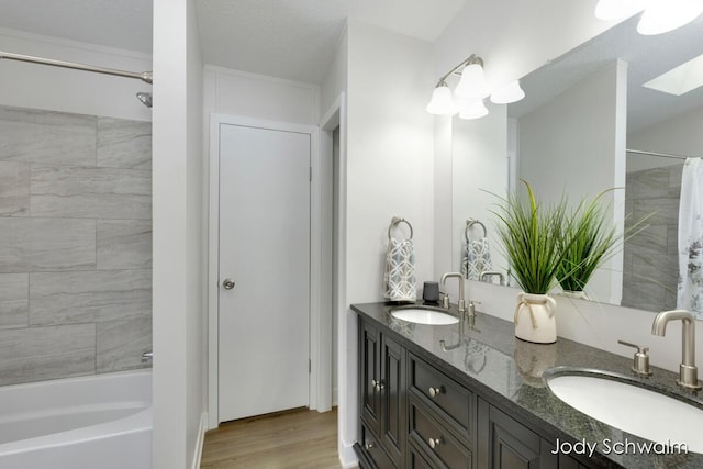 bathroom featuring vanity, hardwood / wood-style floors, shower / bath combo with shower curtain, and a textured ceiling