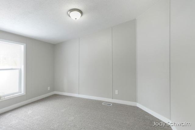 carpeted empty room featuring a textured ceiling