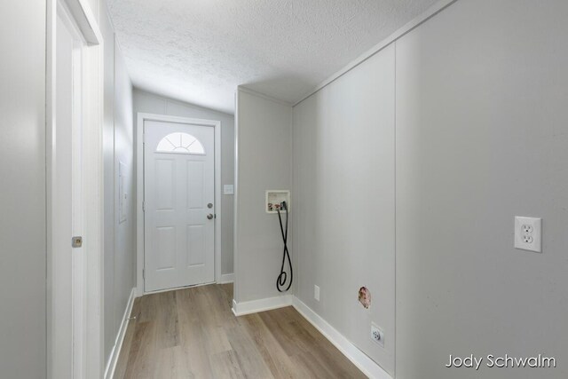 interior space with hookup for a washing machine, a textured ceiling, and light wood-type flooring