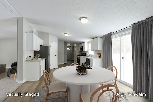 dining area featuring sink, light hardwood / wood-style floors, and a textured ceiling