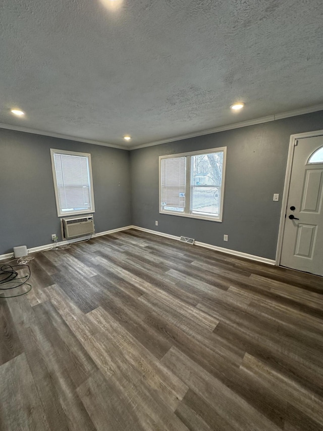 spare room featuring a wall mounted air conditioner, ornamental molding, dark hardwood / wood-style floors, and a textured ceiling